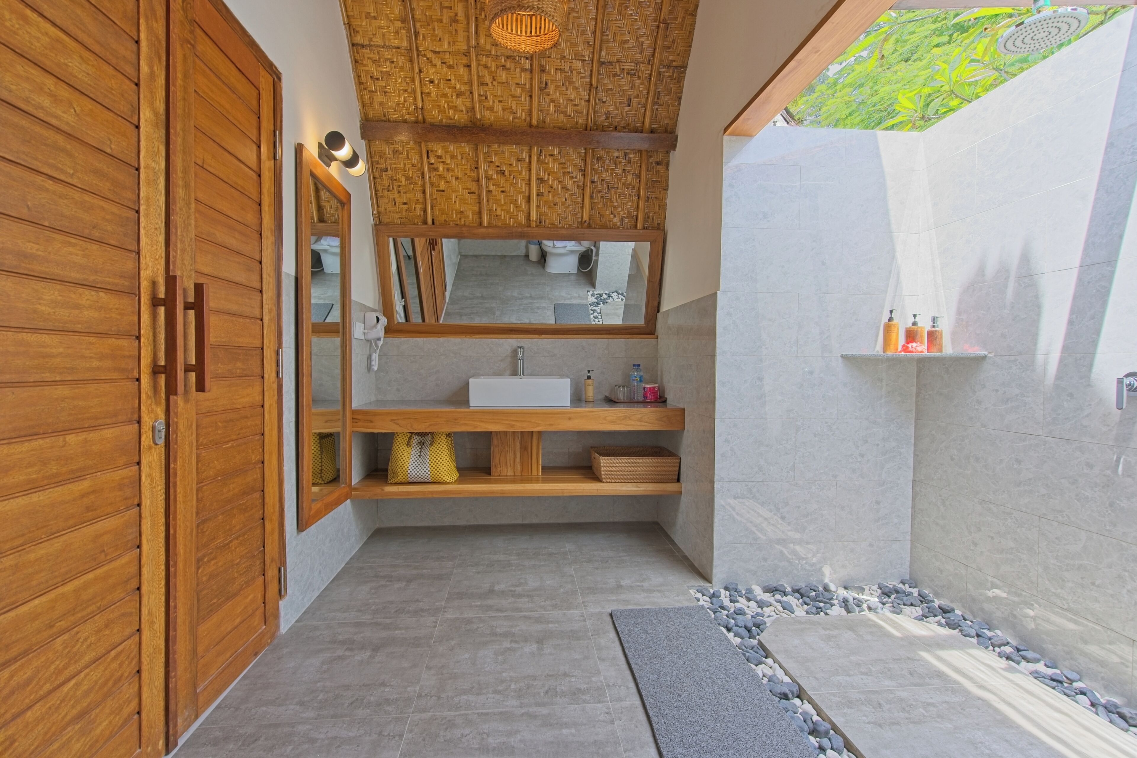 A modern bathroom with a wooden vanity, a large mirror, and a shower area.