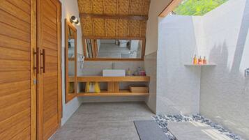 A modern bathroom with a wooden vanity, a large mirror, and a shower area.