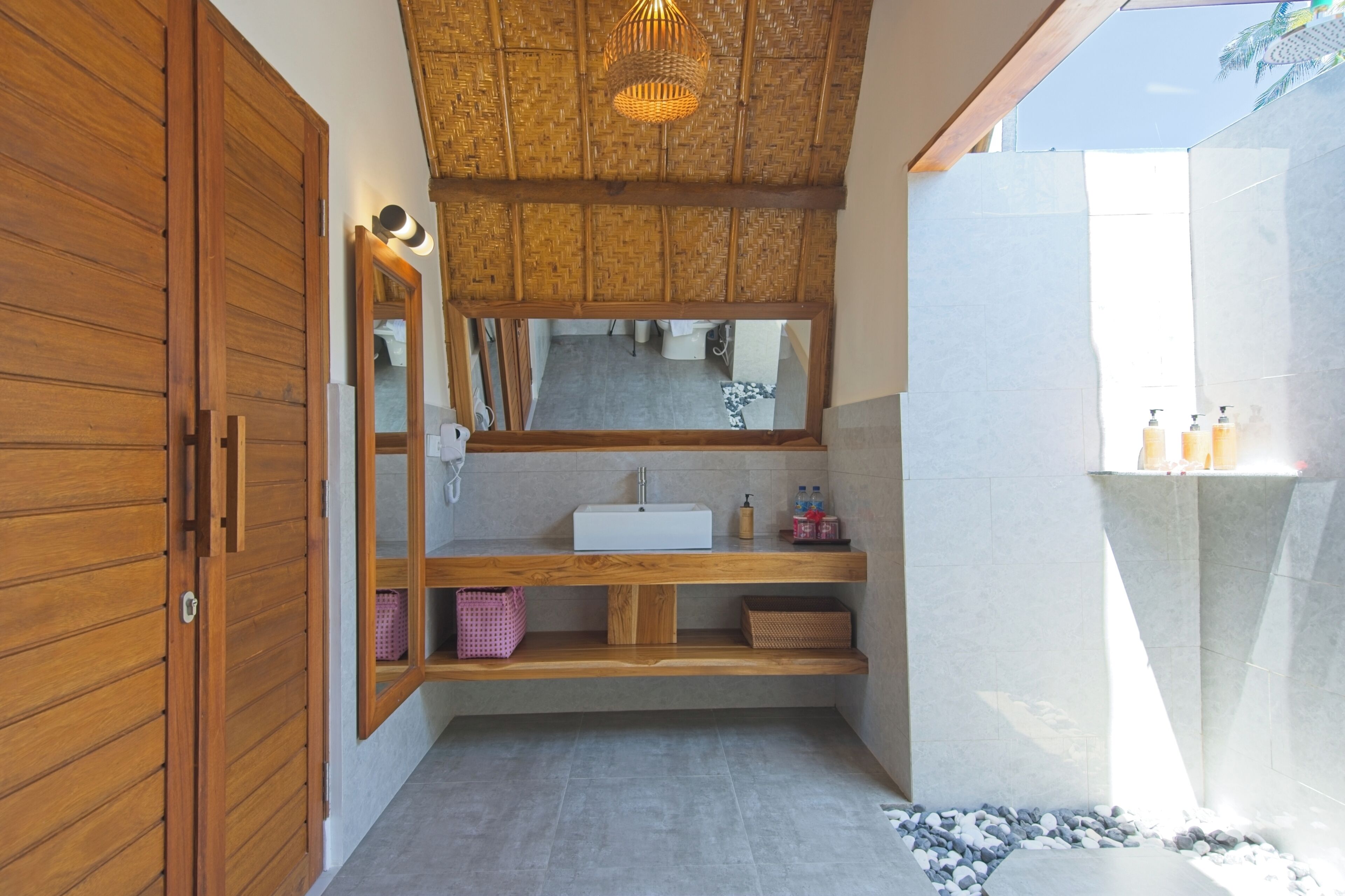 Un baño con tocador de madera, un espejo grande, un lavabo blanco y una zona de ducha.