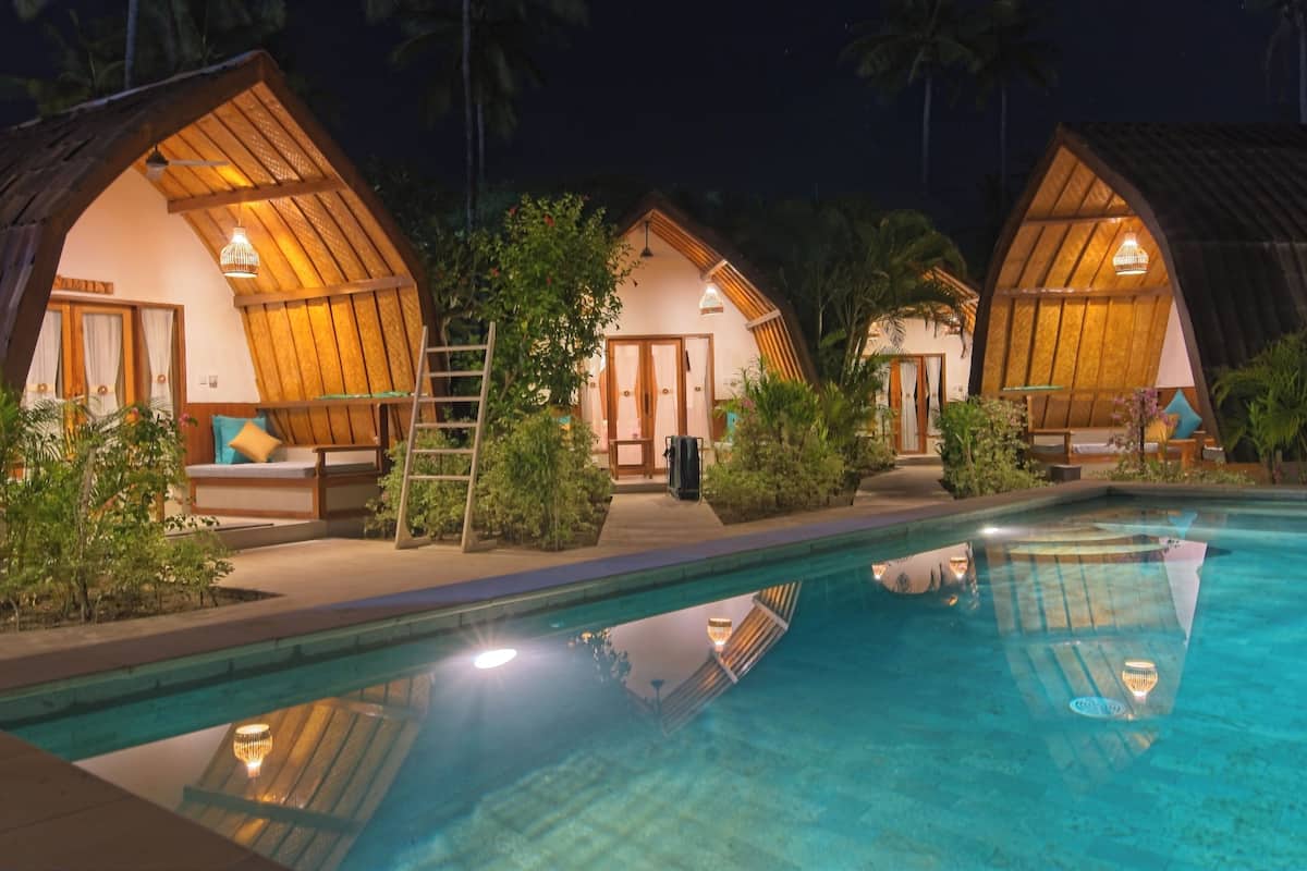A resort with three wooden cottages, each with a balcony and a pool.