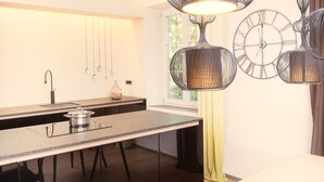 Une cuisine moderne dotée d’un long plan de travail, d’un évier et de luminaires suspendus.
