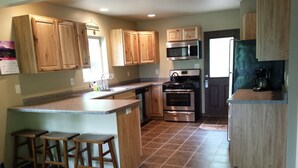 A kitchen with wooden cabinets, a stainless steel oven, a microwave, and a coffee maker. - Lake House - Includes 24' Pontoon, Sleeps 12, Great For Families! (Blackwell)