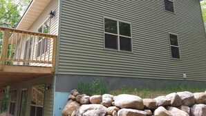 A two-story house with a wooden deck and a stone wall. - Lake House - Includes 24' Pontoon, Sleeps 12, Great For Families! (Blackwell)