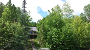 A lakeside cabin with a dock and a bench, surrounded by dense forest. - Lake House - Includes 24' Pontoon, Sleeps 12, Great For Families! (Blackwell)