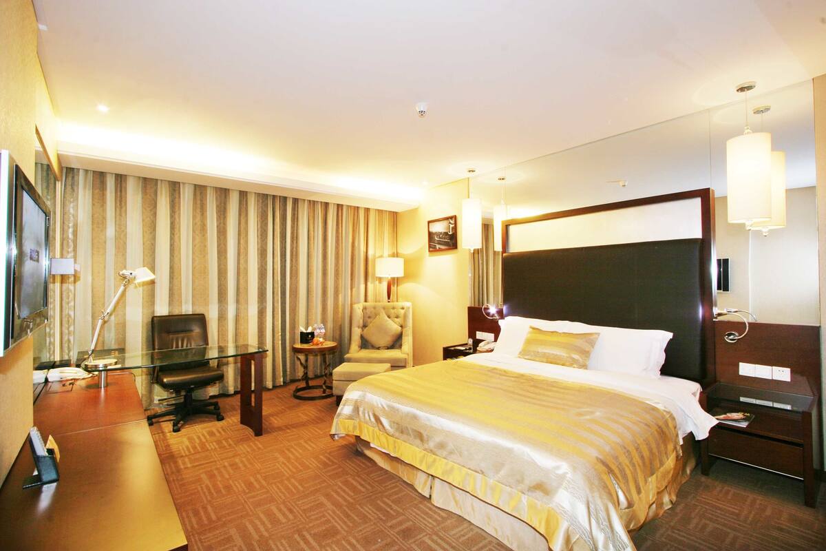 Une chambre d’hôtel avec un grand lit, un bureau équipé d’un ordinateur, une chaise, une lampe et un téléviseur.