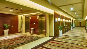 A hotel lobby with a long corridor, elevators, potted plants, and a patterned carpet. - Changsha Xiaoxiang Huatian Hotel (Changsha)