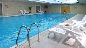 An indoor swimming pool with clear blue water, surrounded by white lounge chairs and a tiled floor. - Changsha Xiaoxiang Huatian Hotel (Changsha)