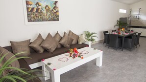 A modern living room with a sofa, coffee table, and dining area. - KyGunAya Villa (Gili Air)