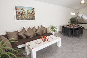 A modern living room with a sofa, coffee table, and dining area.