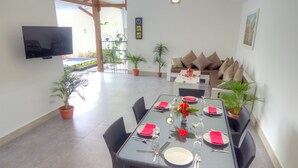 A dining area with a glass table set for six, surrounded by wicker chairs. - KyGunAya Villa (Gili Air)