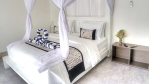 A bed with a canopy, a bedside table with a vase, and a remote control on the table. - KyGunAya Villa (Gili Air)