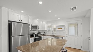 Una cocina moderna con armarios blancos, electrodomésticos de acero inoxidable, encimeras de granito y una isla grande.