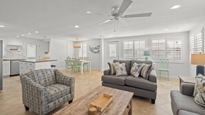 Un amplio espacio habitable con un sofá gris, un sillón estampado y una mesa de centro de madera.