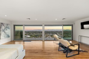 A spacious room with a large sliding glass door leading to a balcony, a white sofa, and a modern chair.
