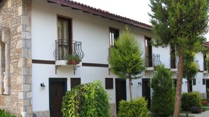 A row of white buildings with stone facades, balconies with potted plants, and a well-maintained garden area. - Aydos Club (Ortaca)