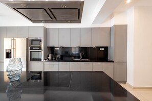 Une cuisine moderne avec un plan de travail noir, des appareils en acier inoxydable et des meubles de couleur grise.