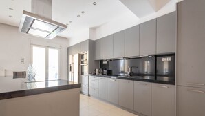 A modern kitchen with grey cabinets, stainless steel appliances, and a central island.