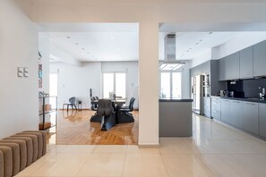 Une cuisine moderne avec des meubles gris, un plan de travail noir et un four encastré.