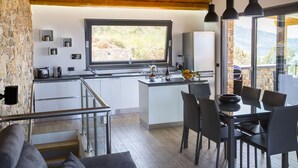 Una cucina moderna con isola centrale, zona pranzo con tavolo e sedie, e vista sull'esterno grazie a ampie finestre.