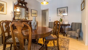 Ein Essbereich mit einem runden Holztisch, sechs Stühlen, einer Chandelüster, einem Spiegel und gerahmten Kunstwerken an den Wänden.