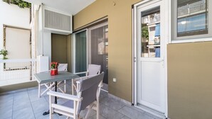 Ein Balkon mit Tisch und Stühlen, einer Schiebetür und Blick auf die Straße.