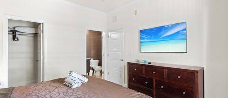 Un dormitorio con cama, cómoda, ventilador de techo y baño con inodoro, además de un cuadro de una playa.