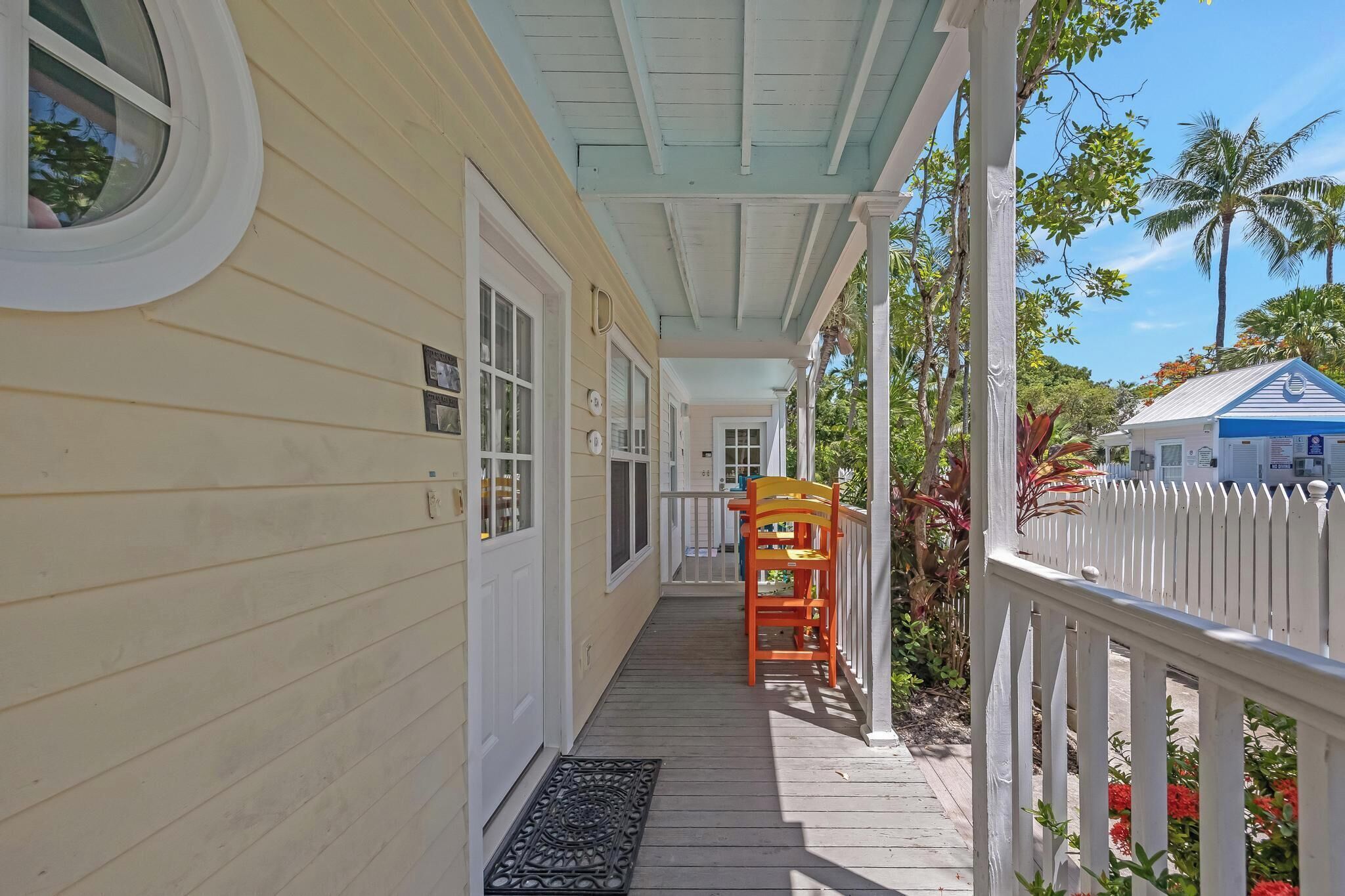 A covered porch with a wooden floor, a white railing, and a small table with chairs.