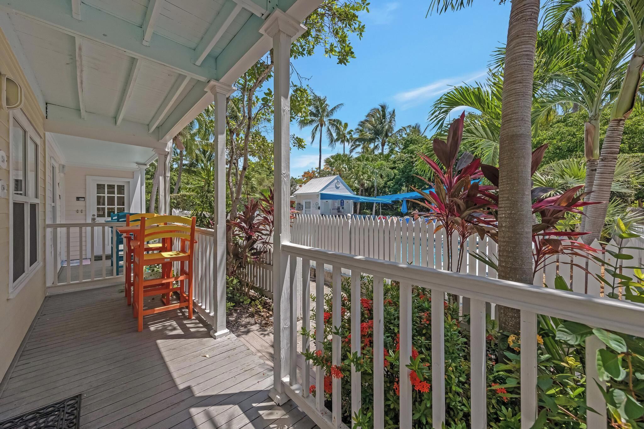 A covered porch with a white railing, wooden deck, and a small table with chairs.