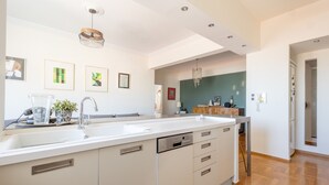 Une cuisine moderne dotée d’un grand îlot central, d’appareils électroménagers en acier inoxydable et donnant sur la salle à manger.