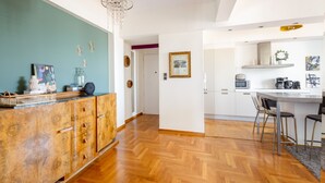 Une cuisine moderne avec des meubles en bois, un coin repas doté de tabourets de bar et un plancher à motifs en chevrons.