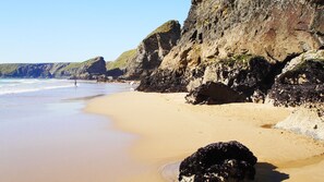 A sandy beach with rocky cliffs and calm waves. - Characterful Cottage near Port Isaac & Polzeath - Fibre Wifi. (Delabole)