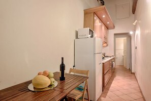 Una cocina compacta con una mesa de madera, un refrigerador y un microondas.