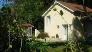 Ein eingeschossiges Haus mit einem geneigten Dach, einer kleinen Veranda und einem Garten.