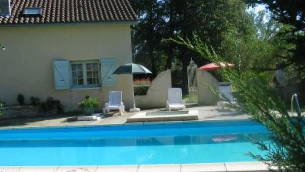 Ein Schwimmbecken mit Liegestühlen und einem Haus im Hintergrund.