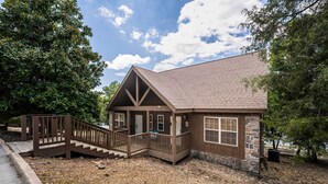 A lodge with a stone facade, wooden deck, and a staircase leading to the entrance.