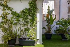 Een binnentuin met plantenpotten en een witte muur.