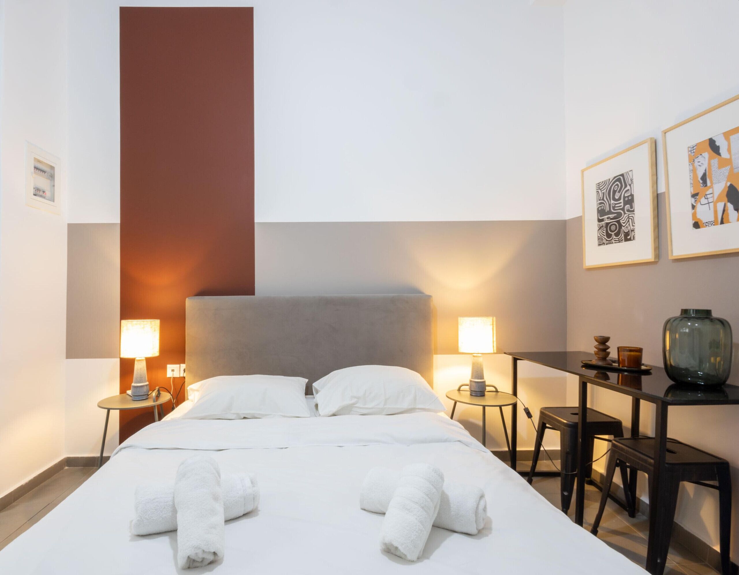 A hotel room with a bed, two bedside tables, a desk, and a chair.