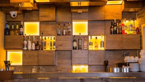 A bar with wooden shelves holding various liquor bottles, illuminated by recessed lighting. - Family Hotel Saint George (Sofia)