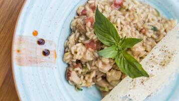 A plate of risotto with a basil garnish and a piece of bread on the side.