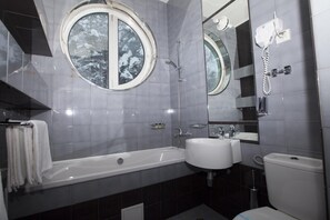 Un baño moderno con bañera, dos lavabos, inodoro y un espejo grande.