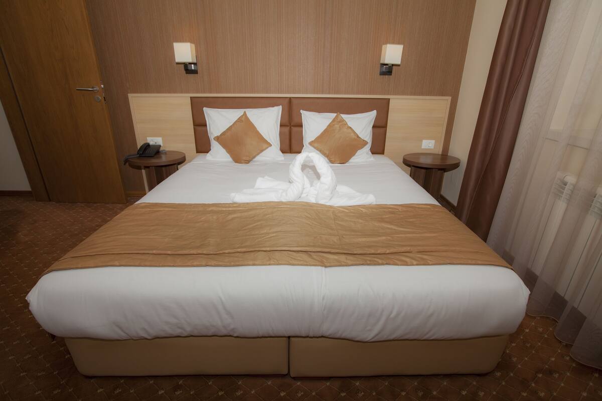 Een hotelkamer met een groot bed, twee nachtkastjes en een houten hoofdeinde.