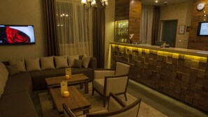 A modern hotel lobby with a reception desk, a large sectional sofa, and a small dining area with tables and chairs. - Family Hotel Saint George (Sofia)