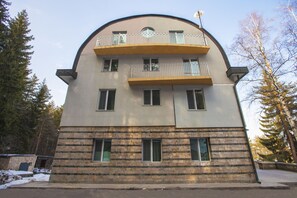 Un edificio de varios pisos con fachada curva, balcones y una base de piedra.
