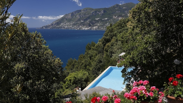 A pool surrounded by lush greenery and a mountainous backdrop.
