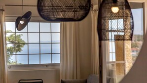 A room with a large window, a chair, and a hanging light fixture.