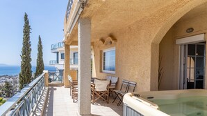 A balcony with a hot tub, outdoor seating, and a view of the sea.