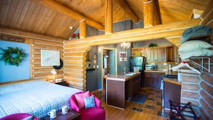 A log cabin interior with a bedroom, a dining area, and a kitchen. - Cozy Log Home -King bed, full kitchen, bathroom with clawfoot tub, outdoor area  (Talkeetna)