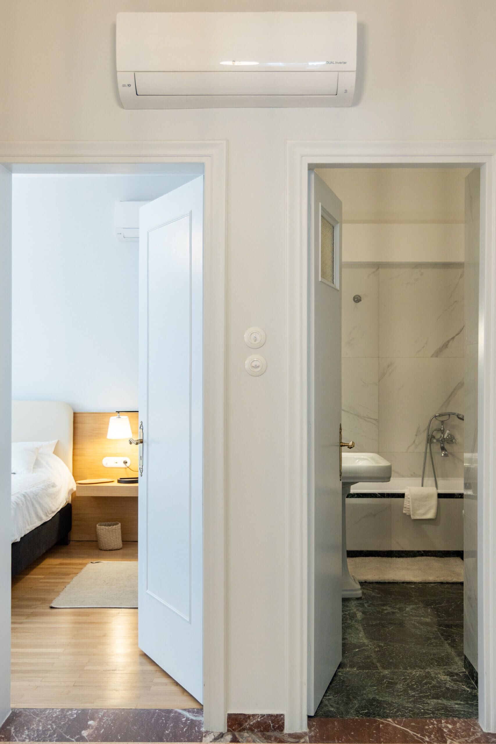 Ein Hotelzimmer mit Bett, Nachttischlampe und einem Badezimmer mit Dusche und Waschbecken.