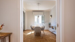 A dining area with a wooden herringbone floor, a round table, and six chairs.