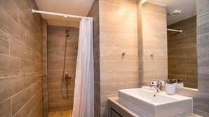 Een moderne badkamer met een douche, een witte wastafel en een spiegel.
